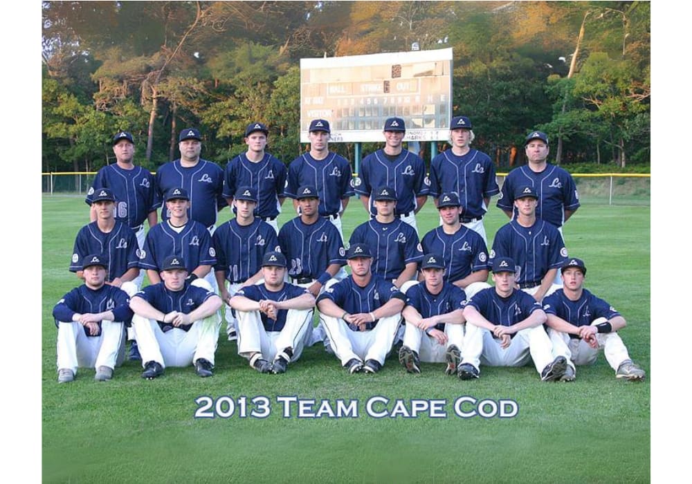 The 2013 Team Cape Cod baseball team posing on the field in navy uniforms